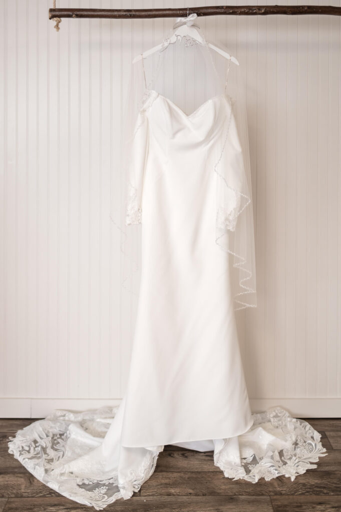 Bridal gown hanging in the suite of The Barn at Whispering Pines, photographed by Lens Love Photography