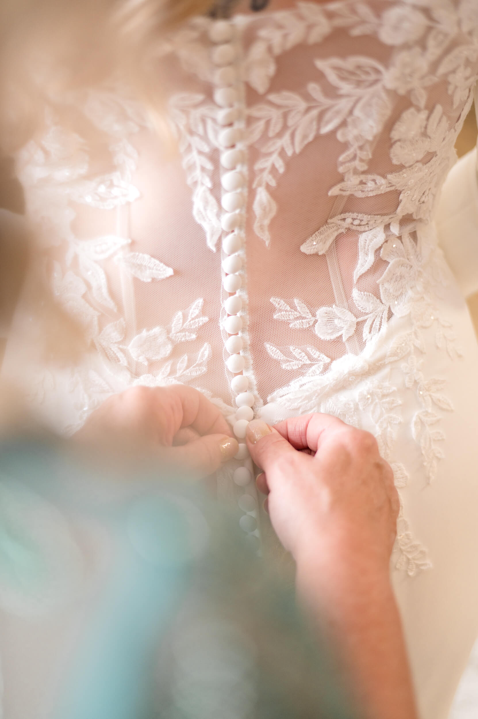 Detail shot of bride's mom buttoning her dress in the suite at The Barn at Whispering Pines, photographed by Lens Love Photography