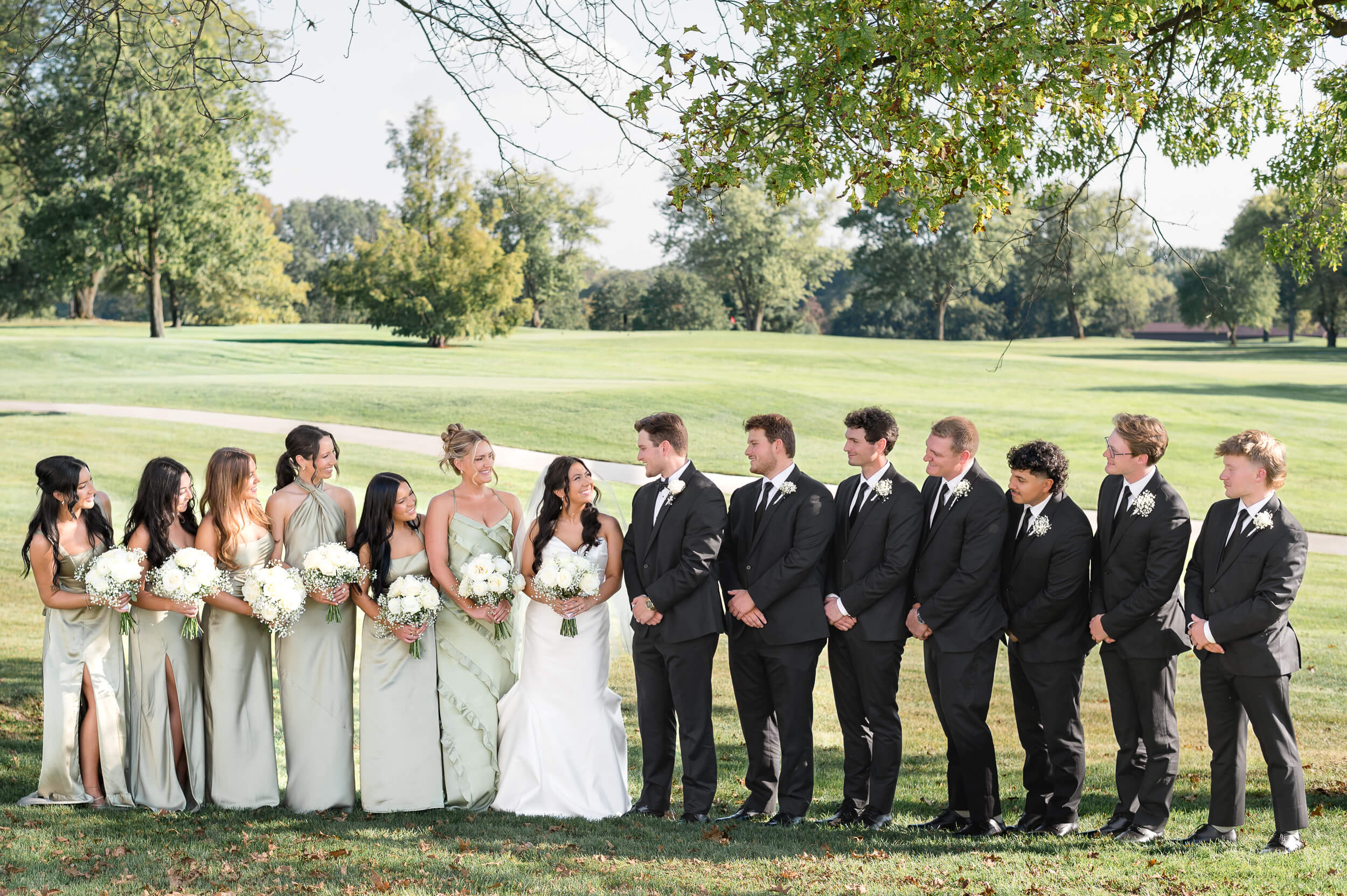 Bride and groom with their wedding party standing on the golf course at Westfield Country Club in Ohio captured by Lens Love Photography.