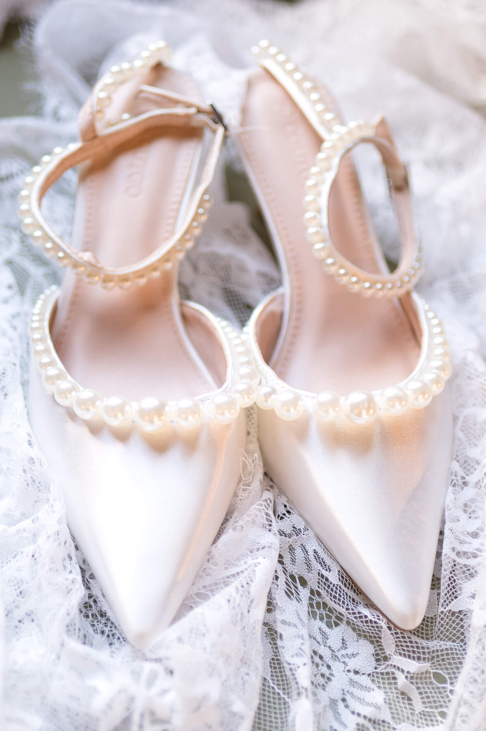 Details of a bride's pearl lined shoes on the veil