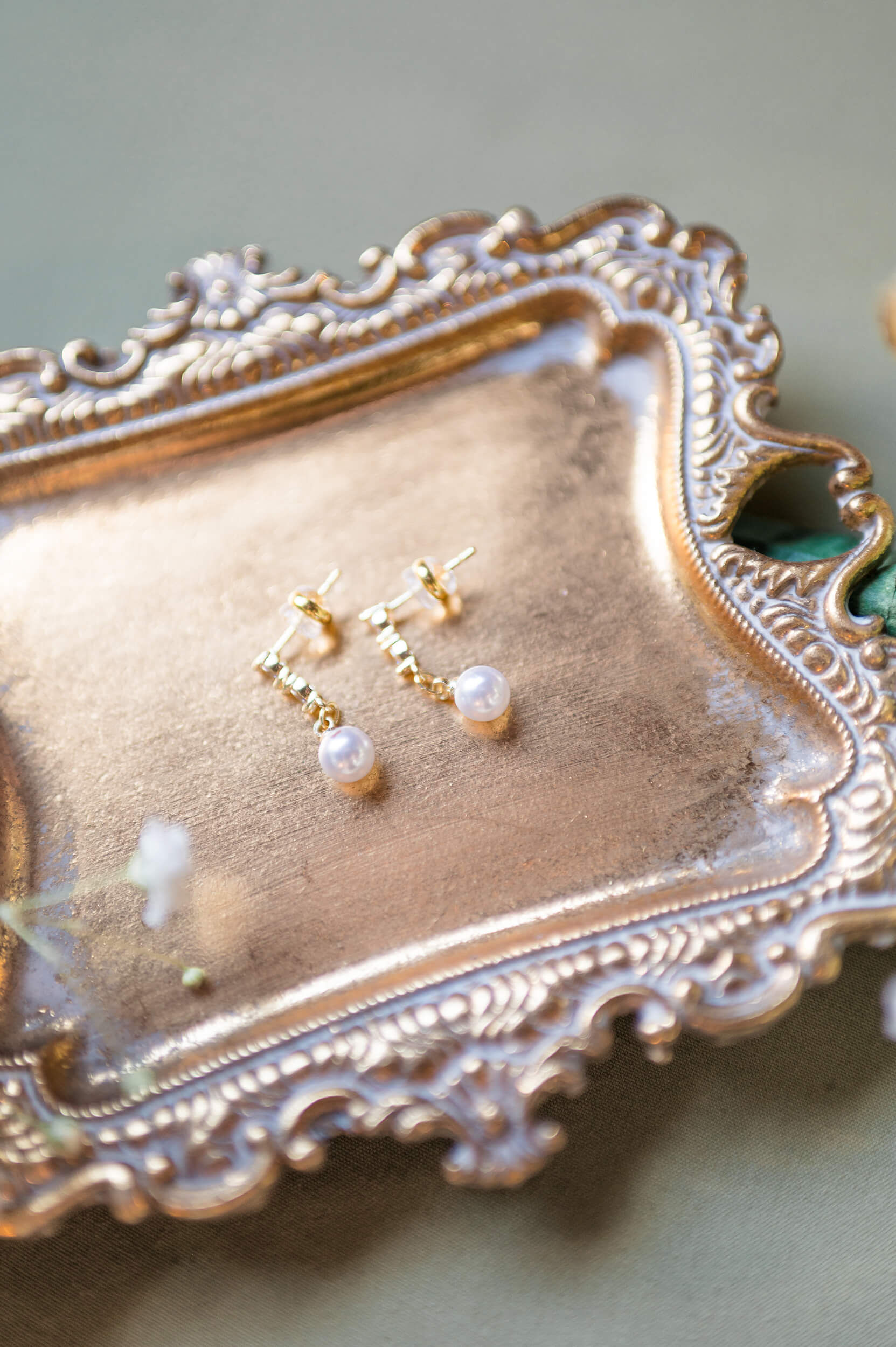 Details of. bride's pearl earrings on a gold tray