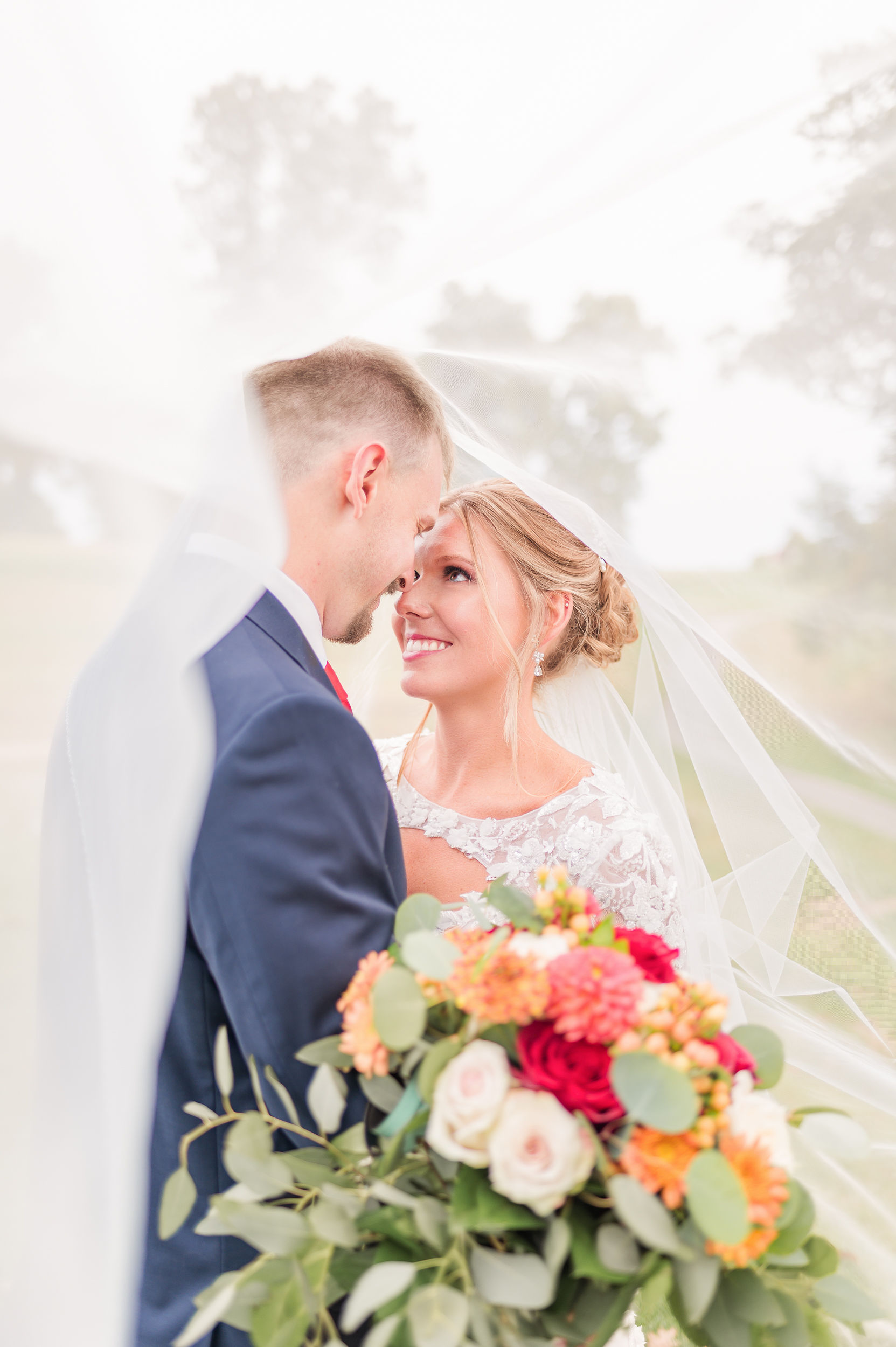 Newlyweds smile at each other while standing nose to nose under the veil in a lawn at one of the outdoor wedding venues in PA