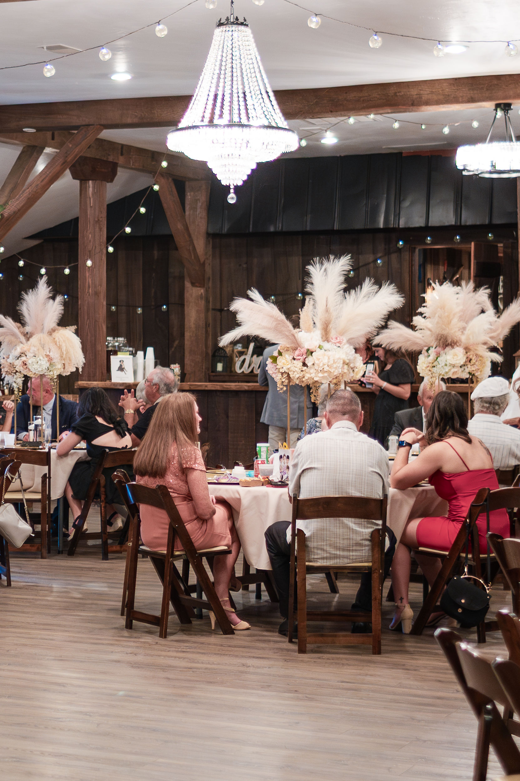 A look at an active wedding reception with tall boho style centerpieces