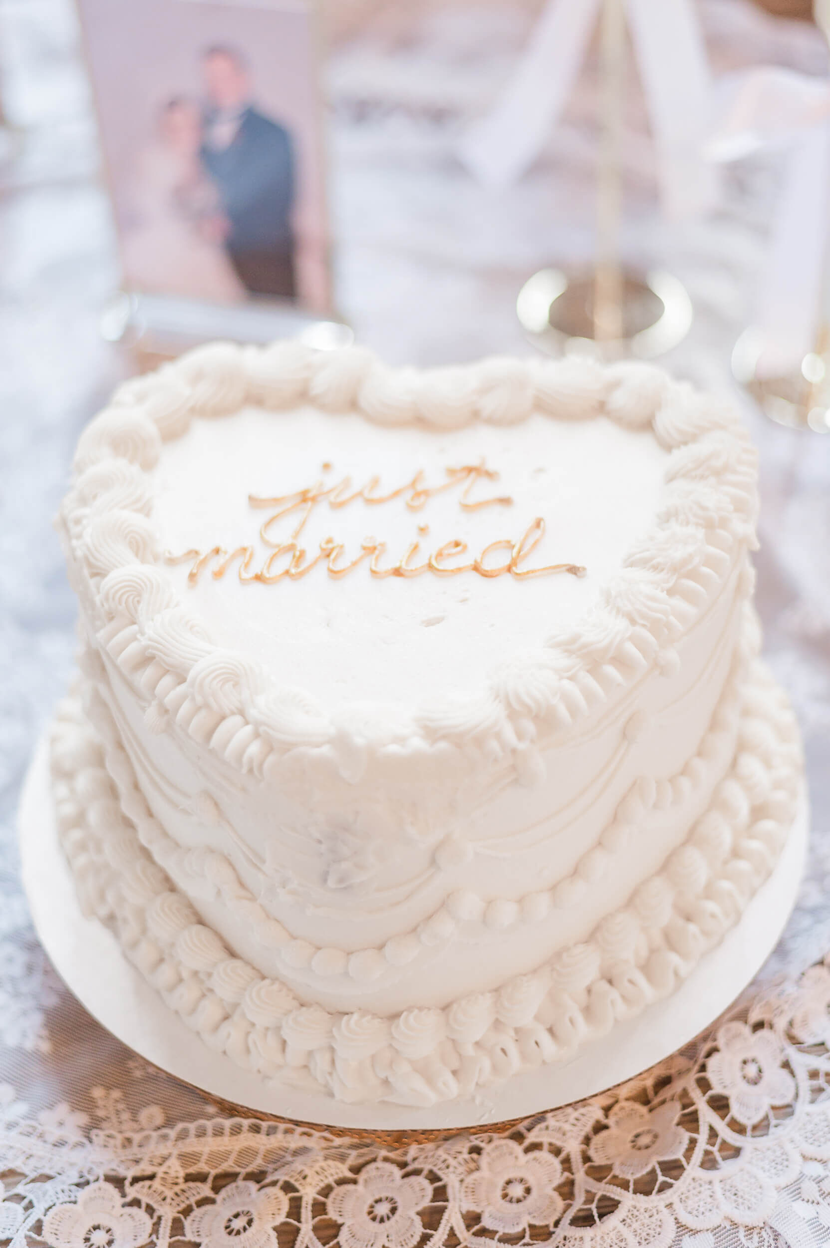 Details of a just married wedding cake on a table with lace tablecloth