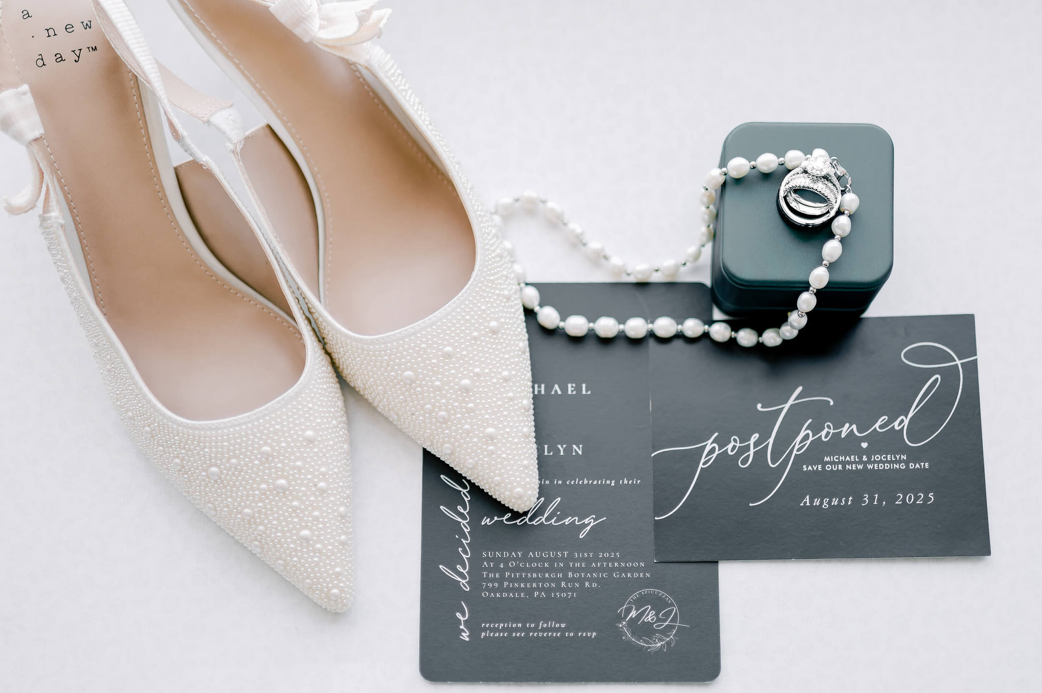 Bridal details of shoes, pearl necklace and rings with invitations