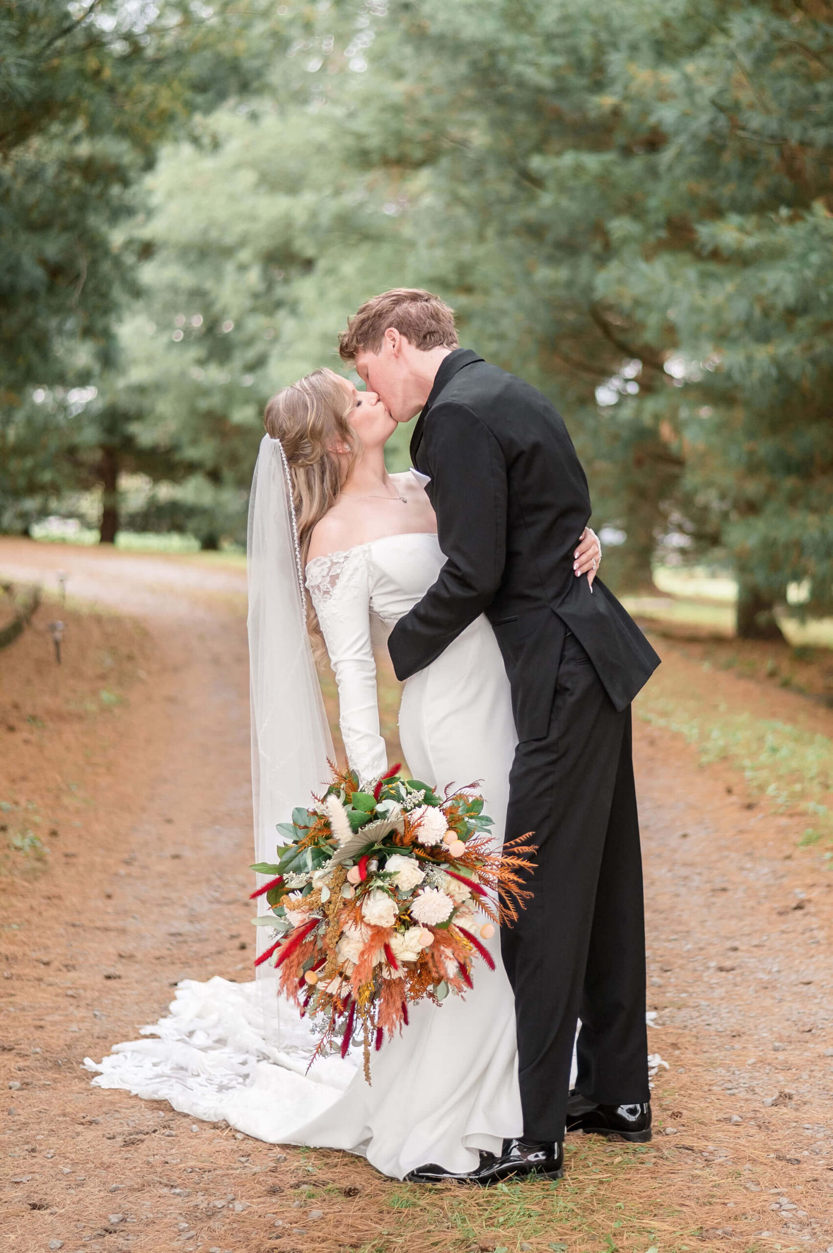 Newlyweds kiss in a pine covered trail at one of the stunning Pennsylvania weddings