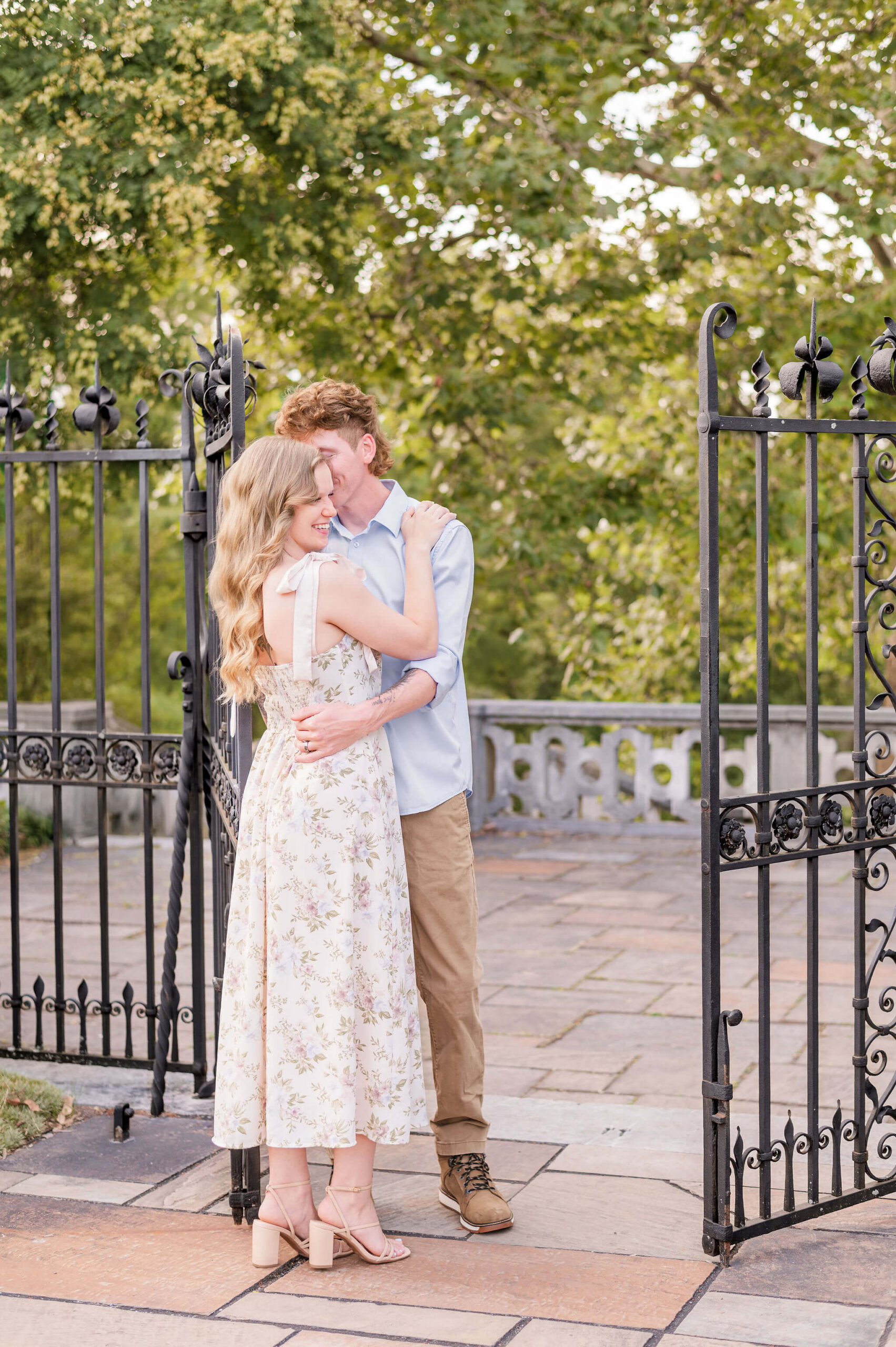 Engaged couple embracing between iron gates during engagement photos at Mellon Park in Pittsburgh.