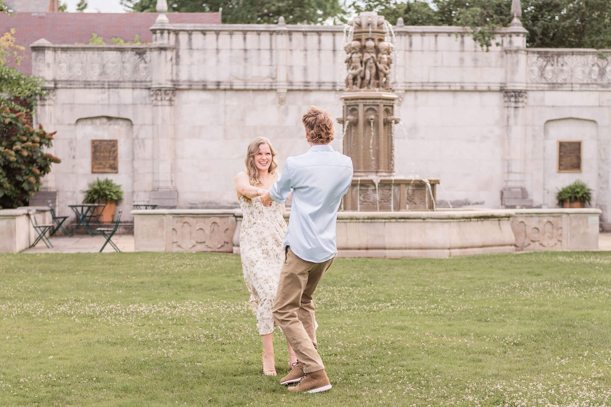 Couple spinning and laughing in front of the fountain during engagement photos at Mellon Park in Pittsburgh