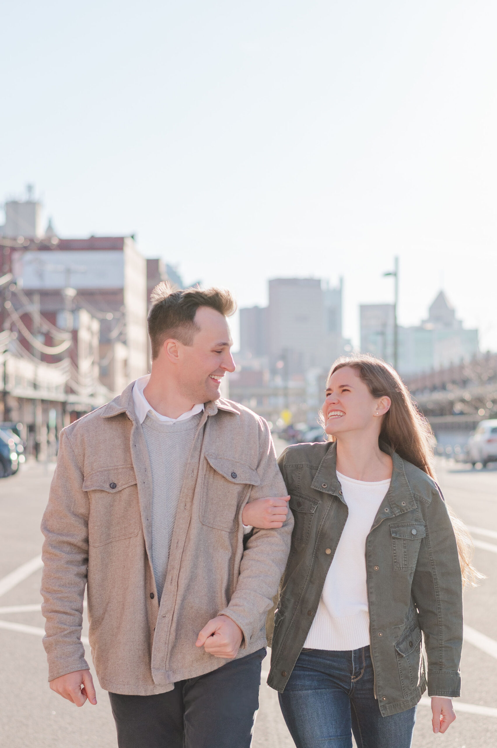 Couple walking down a street for their Strip District engagement photos, holding each other.