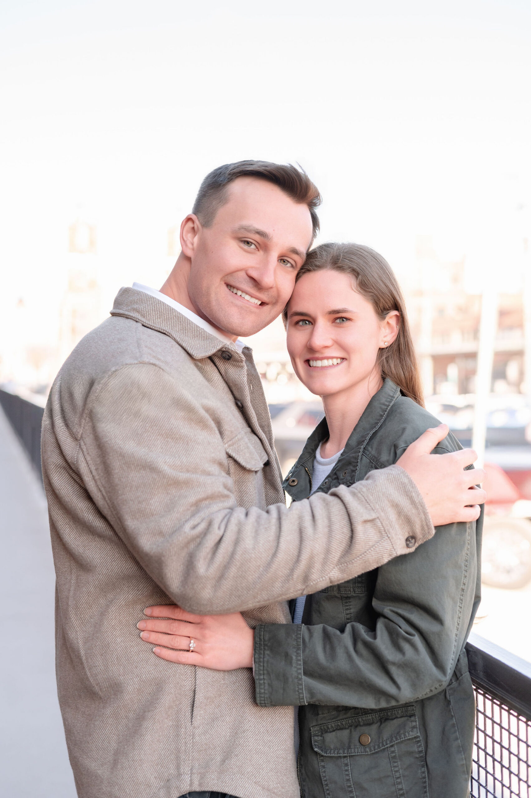 Couple posing together and smiling at the camera for their Strip District engagement photos.
